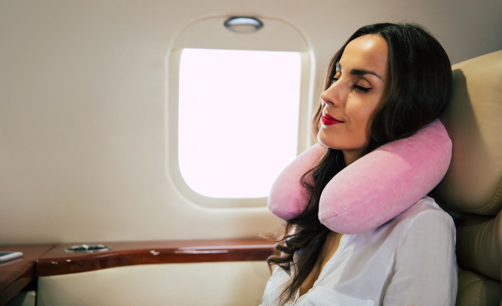 woman_relaxing_with_a_pillow_in_plane_after_hair_transplant_in_turkey
